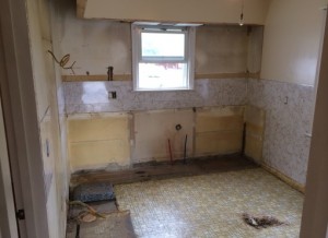 Kitchen space with old cabinets and appliances torn out with bare walls