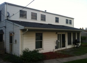 Back of home with white siding before being renovated